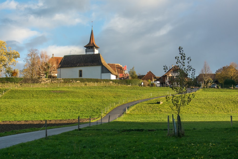 a white church with a steeple on a grassy hill