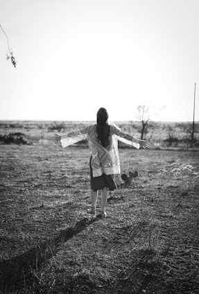 a woman standing in a field with her arms outstretched