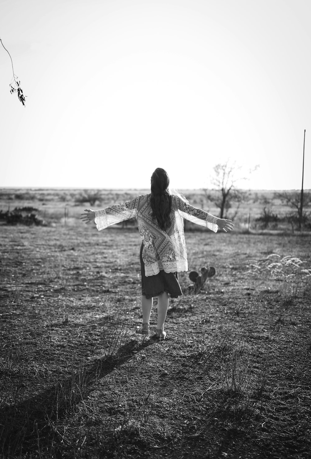 a woman standing in a field with her arms outstretched