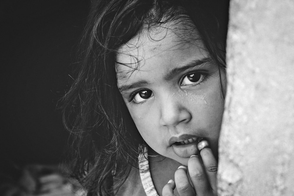 a little girl holding her hand up to her face