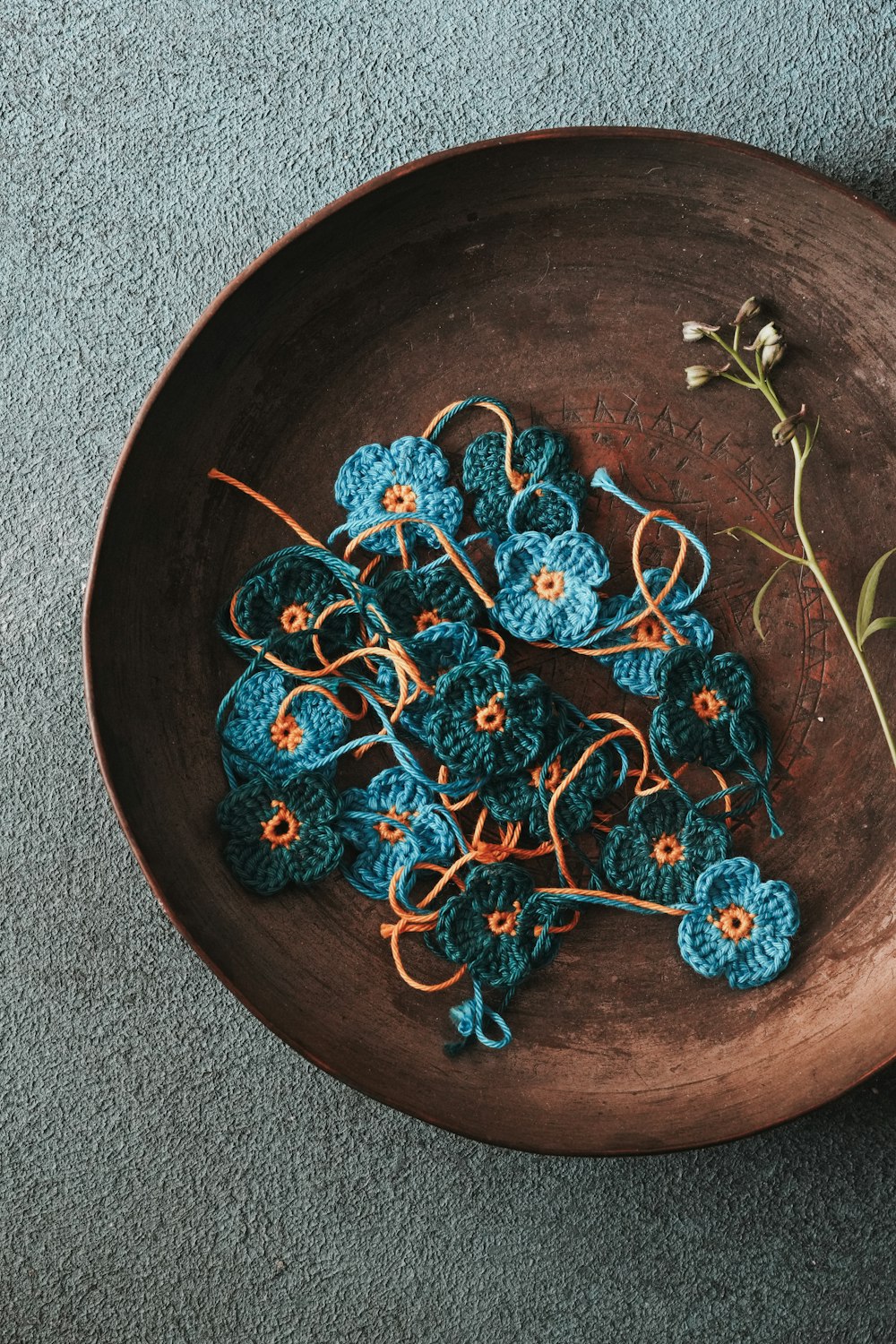 a bowl of crocheted flowers on a gray carpet