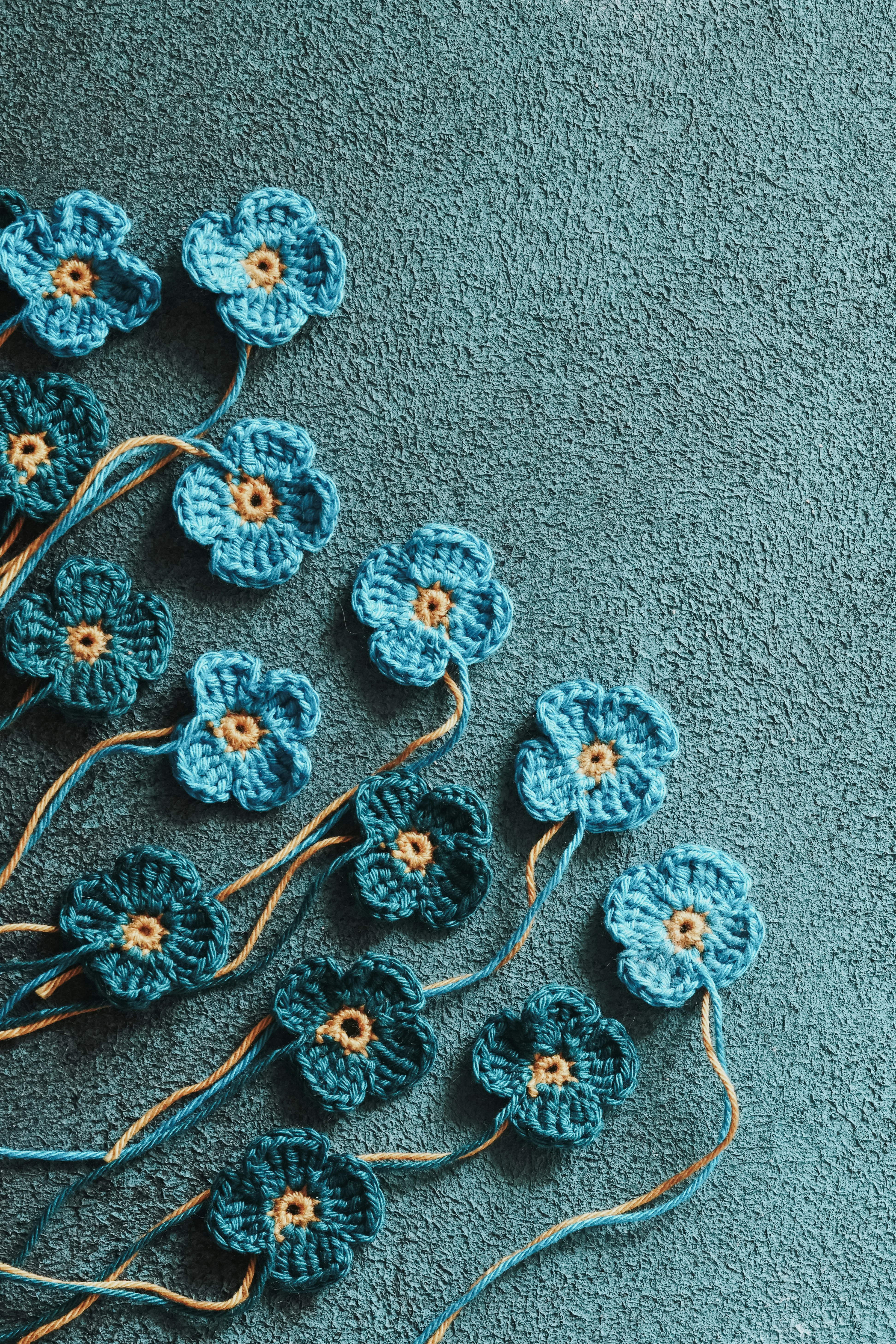 a group of crocheted flowers sitting on a blue surface