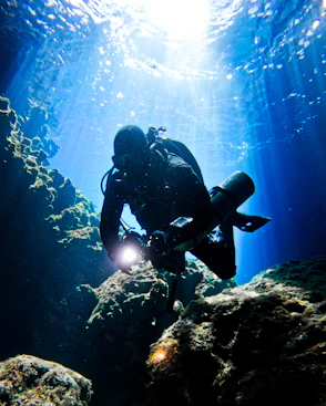 a person scubas in the water near rocks