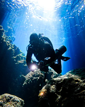 a person scubas in the water near rocks