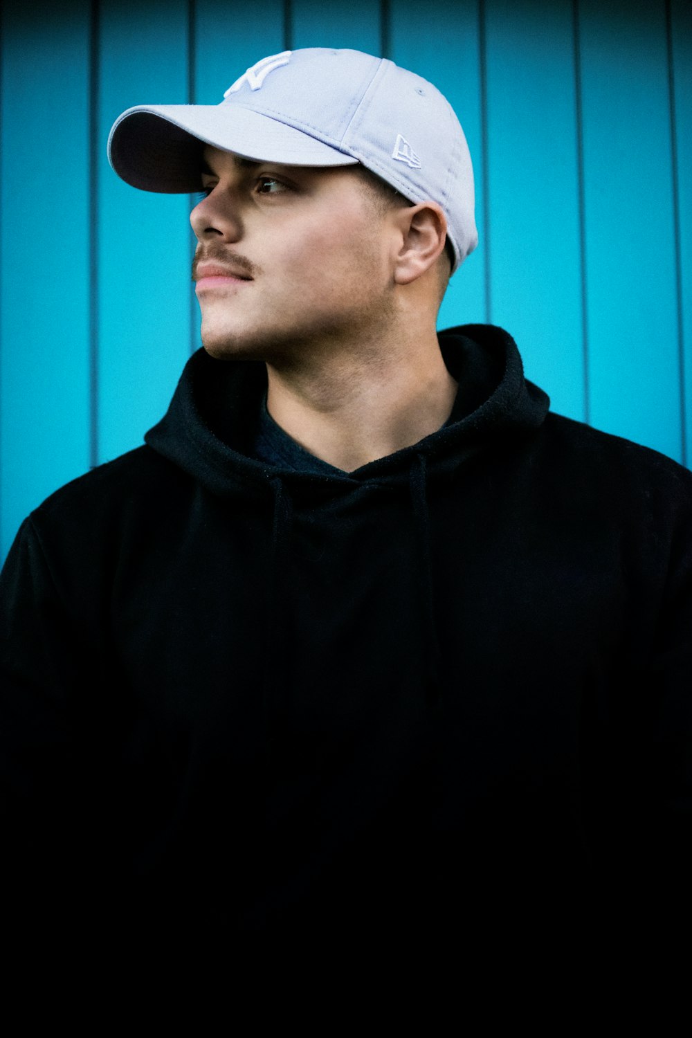 a man in a black hoodie and a white hat
