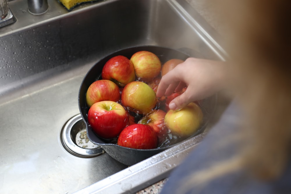 a person washing apples in a sink