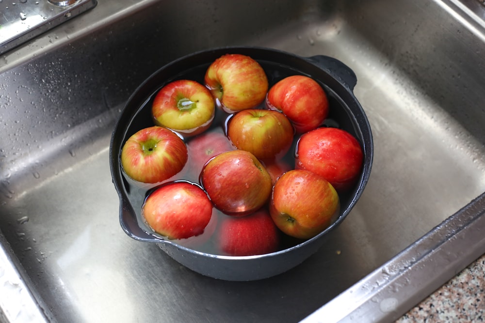 a pan filled with apples sitting on top of a sink