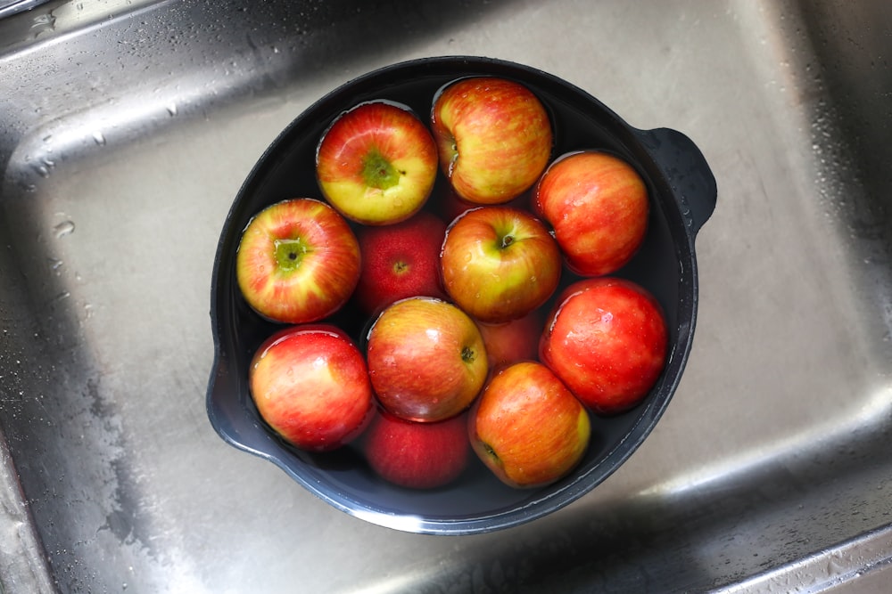 a bowl of apples sitting on top of a sink