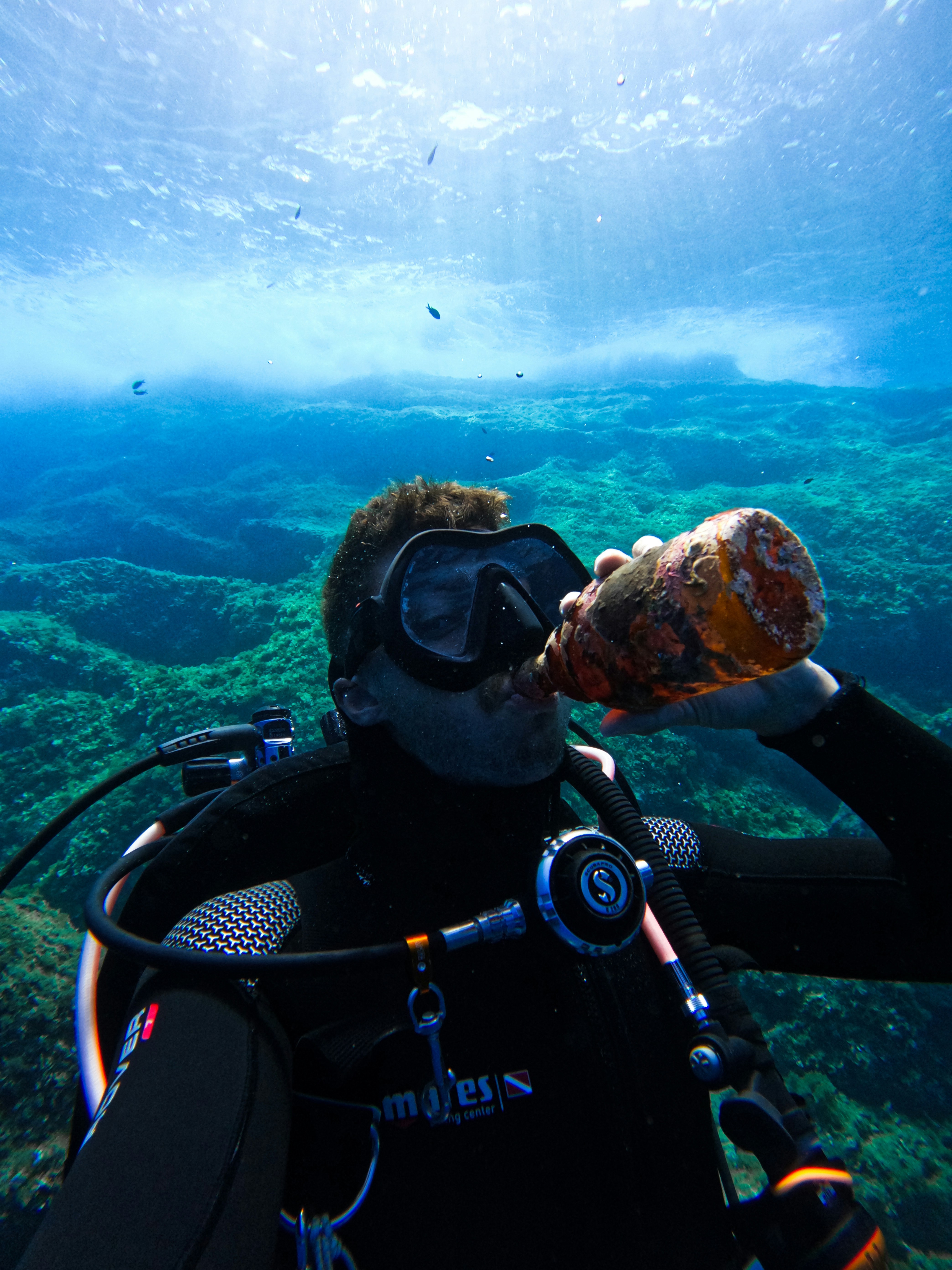 a man in a scuba suit is holding a bottle in the water