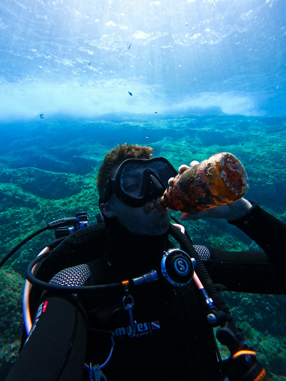 a man in a scuba suit is holding a bottle in the water