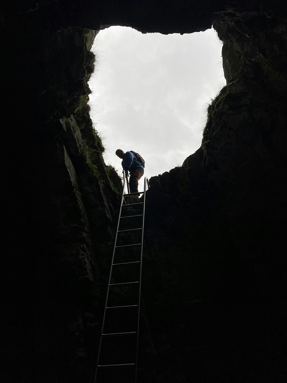 a man climbing up a ladder into a cave