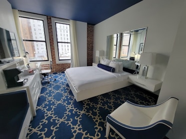 A warmly lit hotel room with plush bedding and elegant navy blue accents.