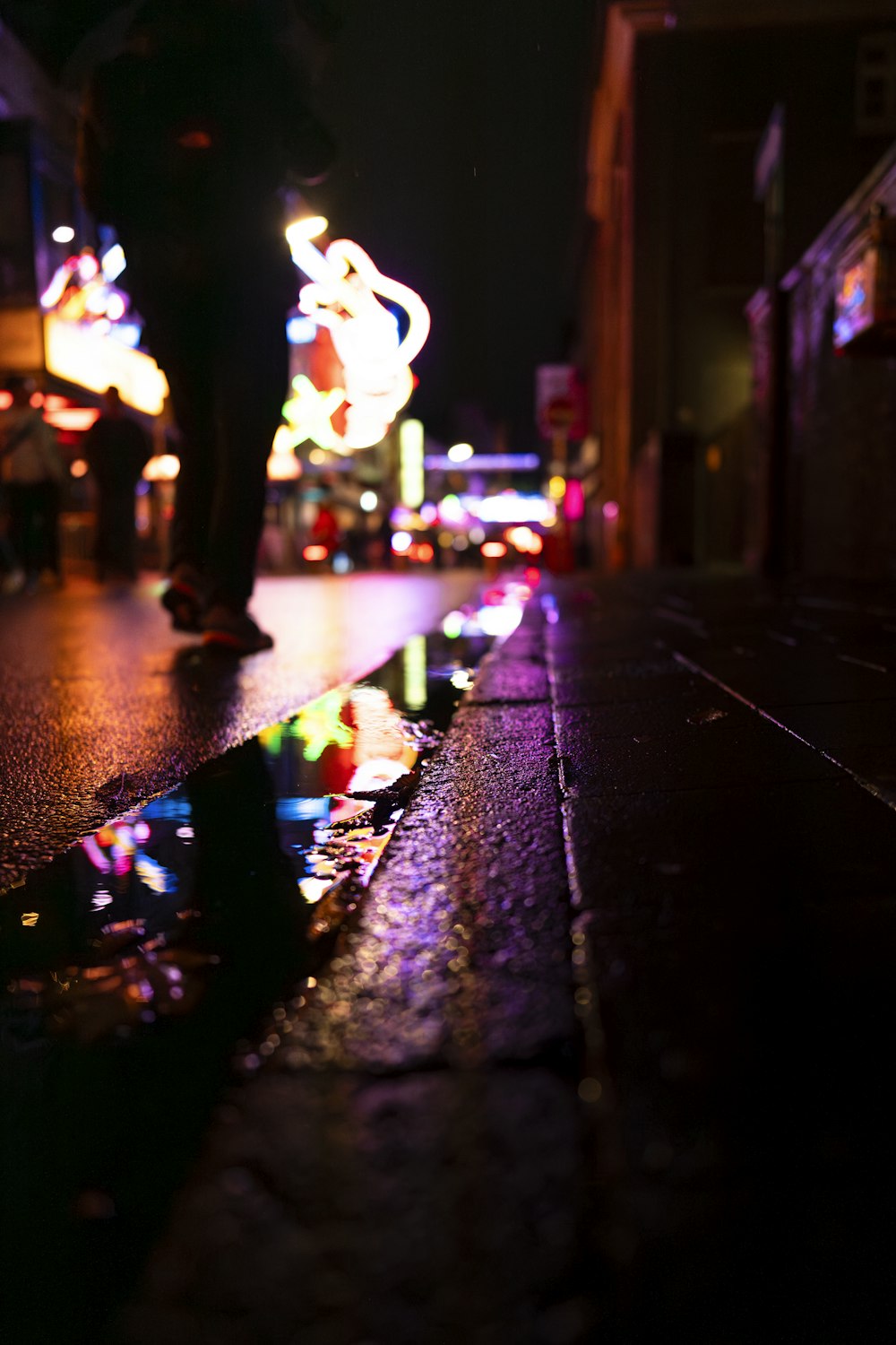 a person walking down a wet street at night