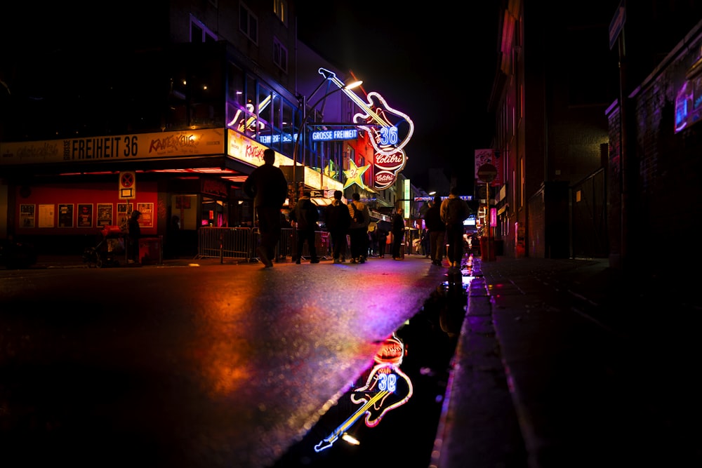 uma cena de rua à noite com pessoas andando na calçada