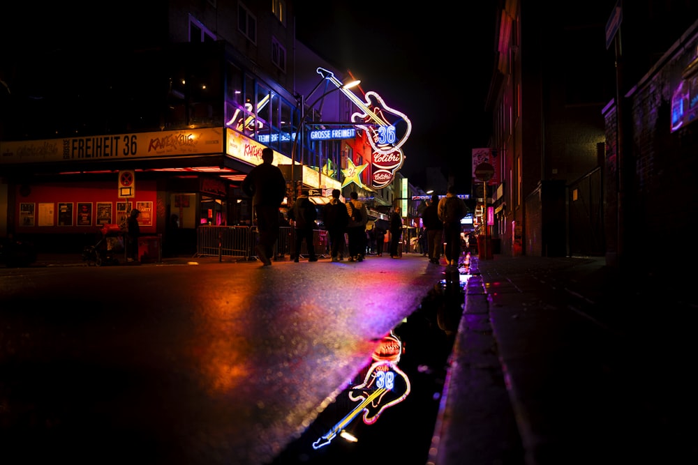 a street scene at night with people walking on the sidewalk