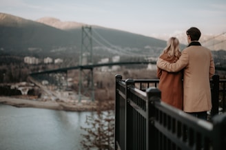 A couple exploring a scenic mountain landscape, holding hands and taking in the view.