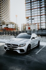 A sleek black Mercedes parked in front of a modern office building at sunset.