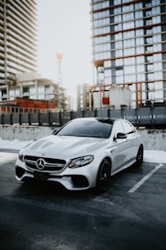 A sleek black Mercedes parked in front of a modern office building at sunset.