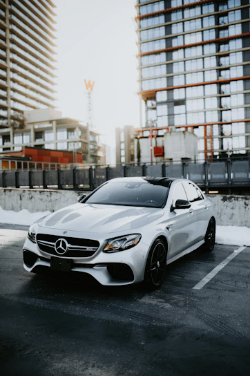 A sleek black Mercedes sedan parked outside a downtown Chicago skyscraper at sunset.