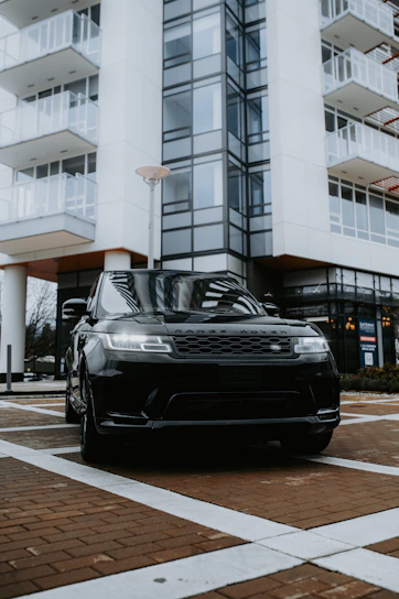 Sleek black Range Rover parked at airport terminal under soft evening lights.