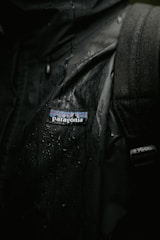 Close-up of a sleek, insulated men's winter jacket with waterproof fabric glistening under soft light.