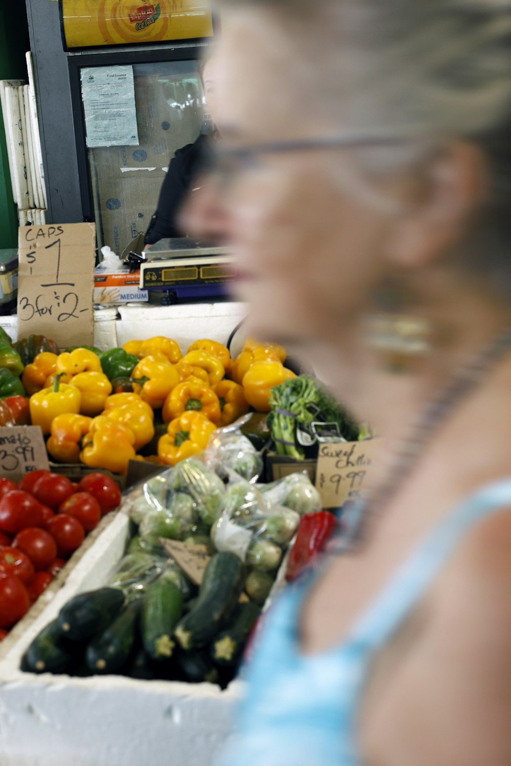 una donna in piedi davanti a un'esposizione di frutta e verdura
