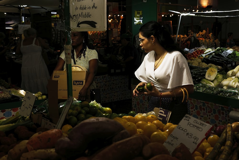 una donna in piedi davanti a un banco di frutta