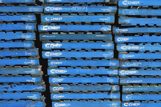 A stack of blue wooden pallets marked with the brand name 'CHEP' in white letters. Each pallet is uniformly colored and arranged tightly together, forming a repetitive pattern.