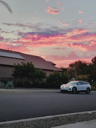 A shiny electric car parked beside a solar-powered home.
