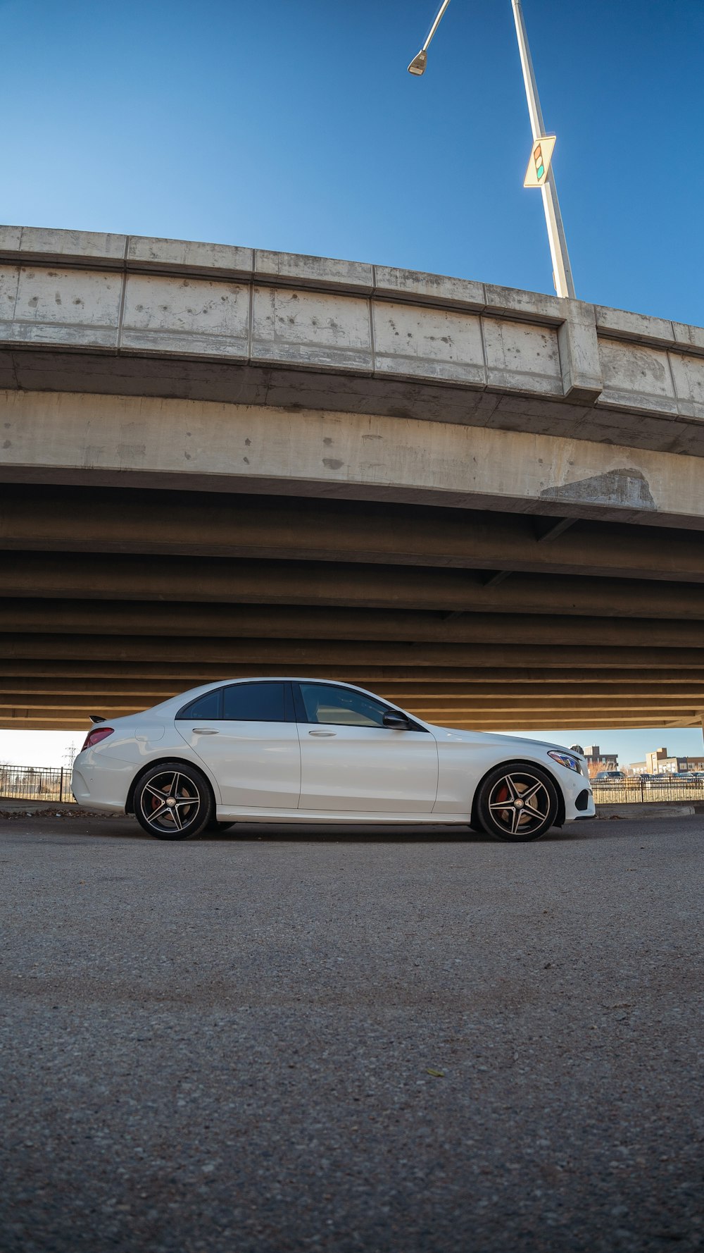 a white car parked in a parking lot under a bridge