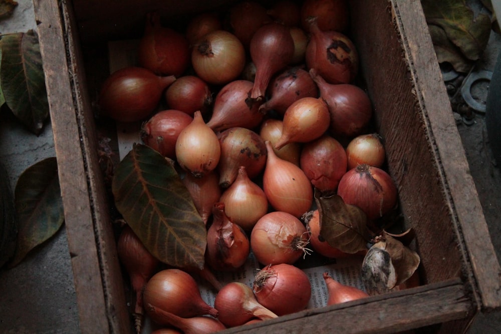 a wooden box filled with lots of red onions