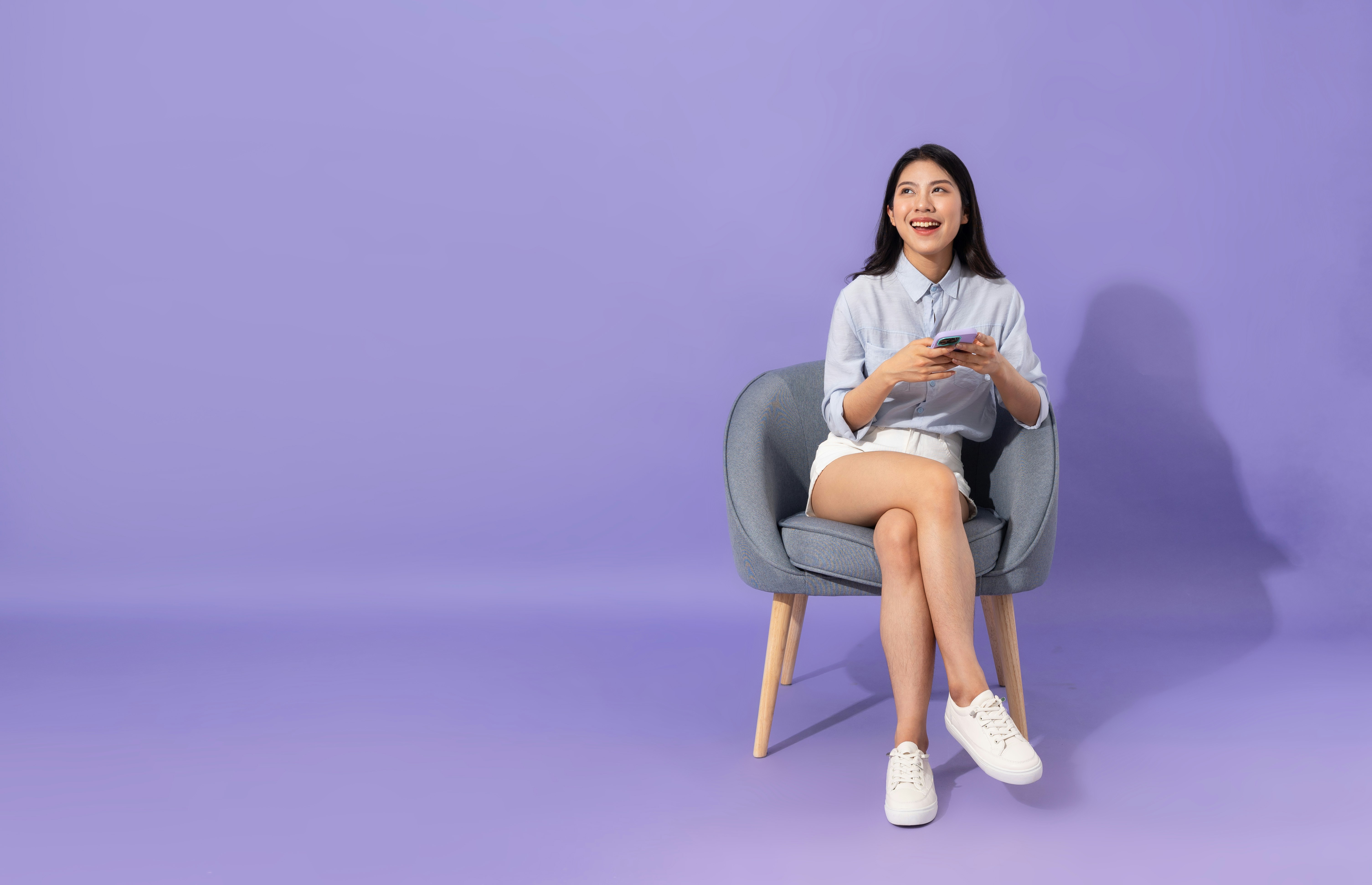 a woman sitting in a chair looking at her cell phone