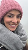 A model wearing a snug, skin-friendly wool hat while smiling outdoors on a chilly day.