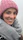 Lifestyle shot of a woman wearing a dusty rose knitted scarf, smiling outdoors on a crisp autumn day.