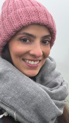 A model wearing a snug, skin-friendly wool hat while smiling outdoors on a chilly day.