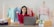 A happy woman holding a tablet, surrounded by office supplies.