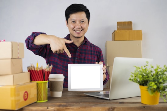 a man pointing at a laptop screen on a desk
