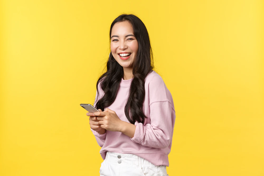 Woman in a pink sweater smiling while reading comments on her phone