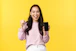 Smiling woman holding her phone, looking relieved and happy after getting a loan approval.
