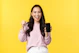 Smiling woman holding her phone, looking relieved and happy after getting a loan approval.