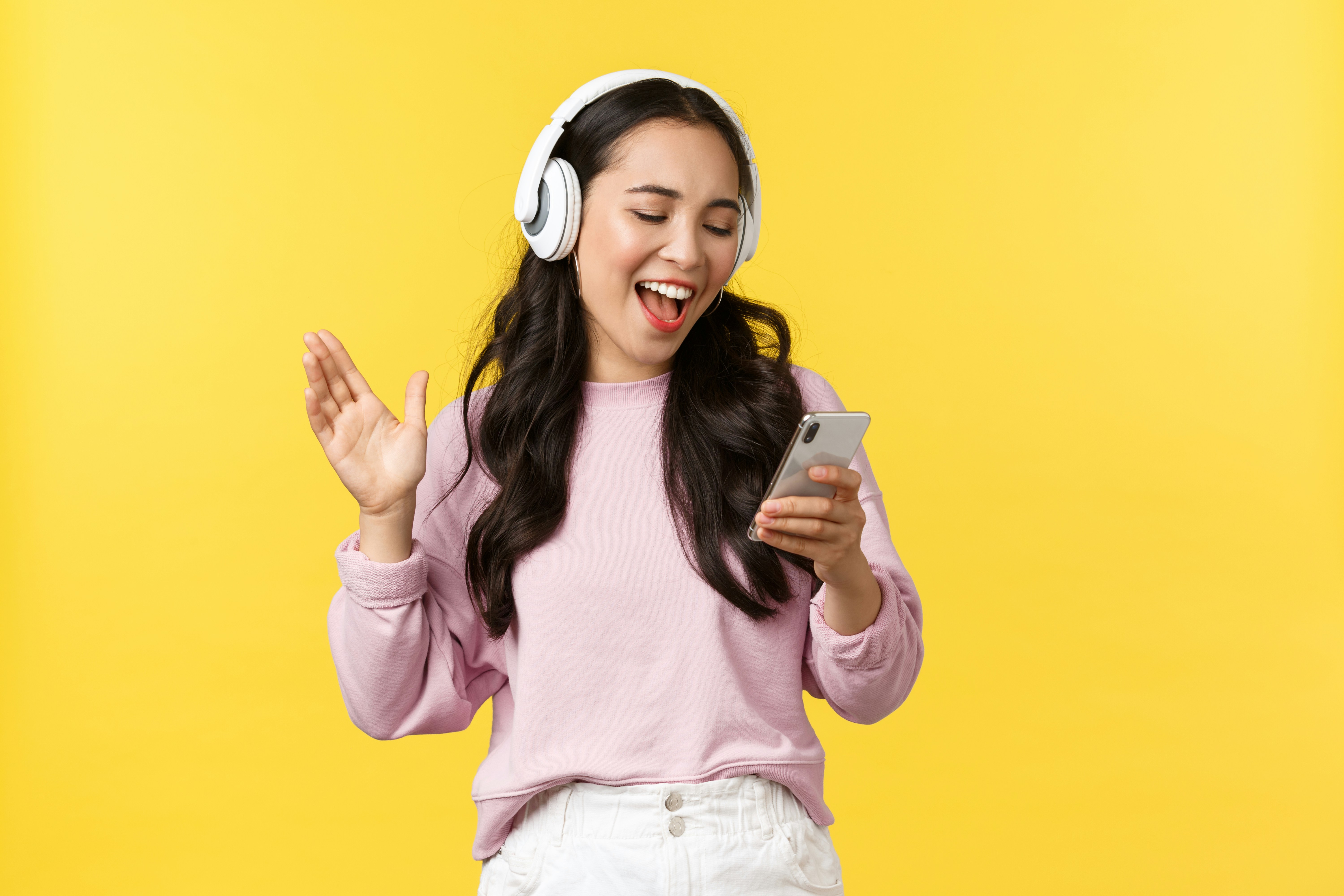 seorang gadis mengenakan headphone dan memegang ponsel