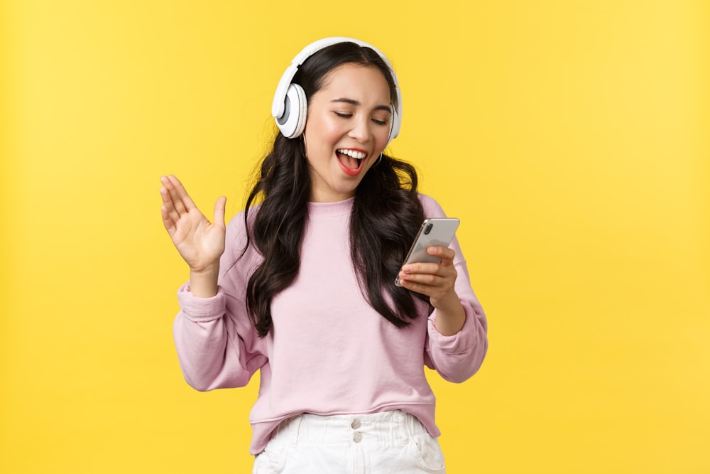 a girl wearing headphones and holding a cell phone
