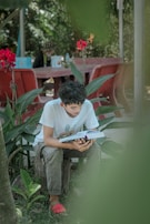 A child sitting under a tree, engrossed in a book.