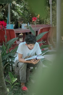 A child sitting under a tree, engrossed in a book.