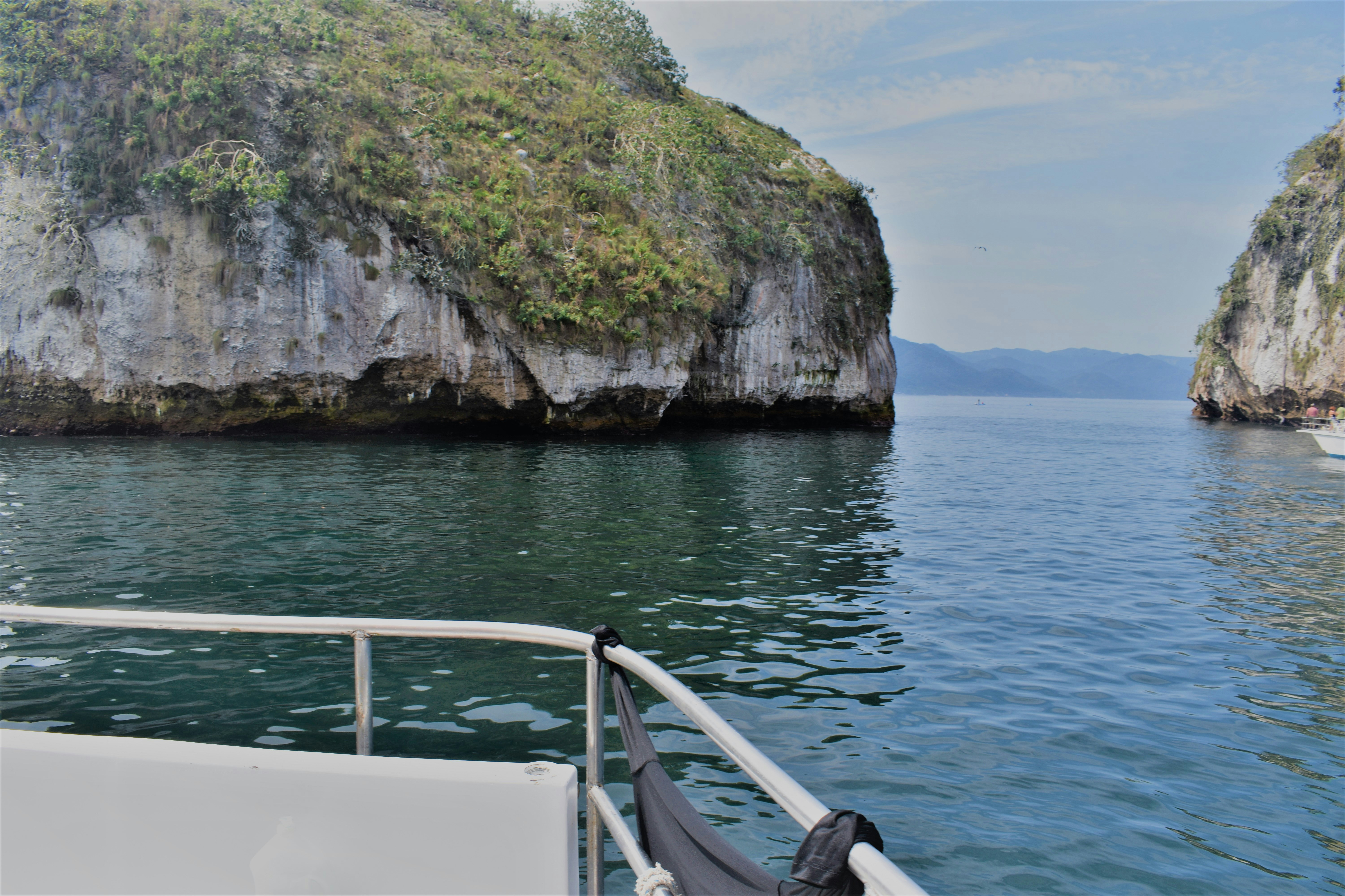a boat traveling past a large rock outcropping