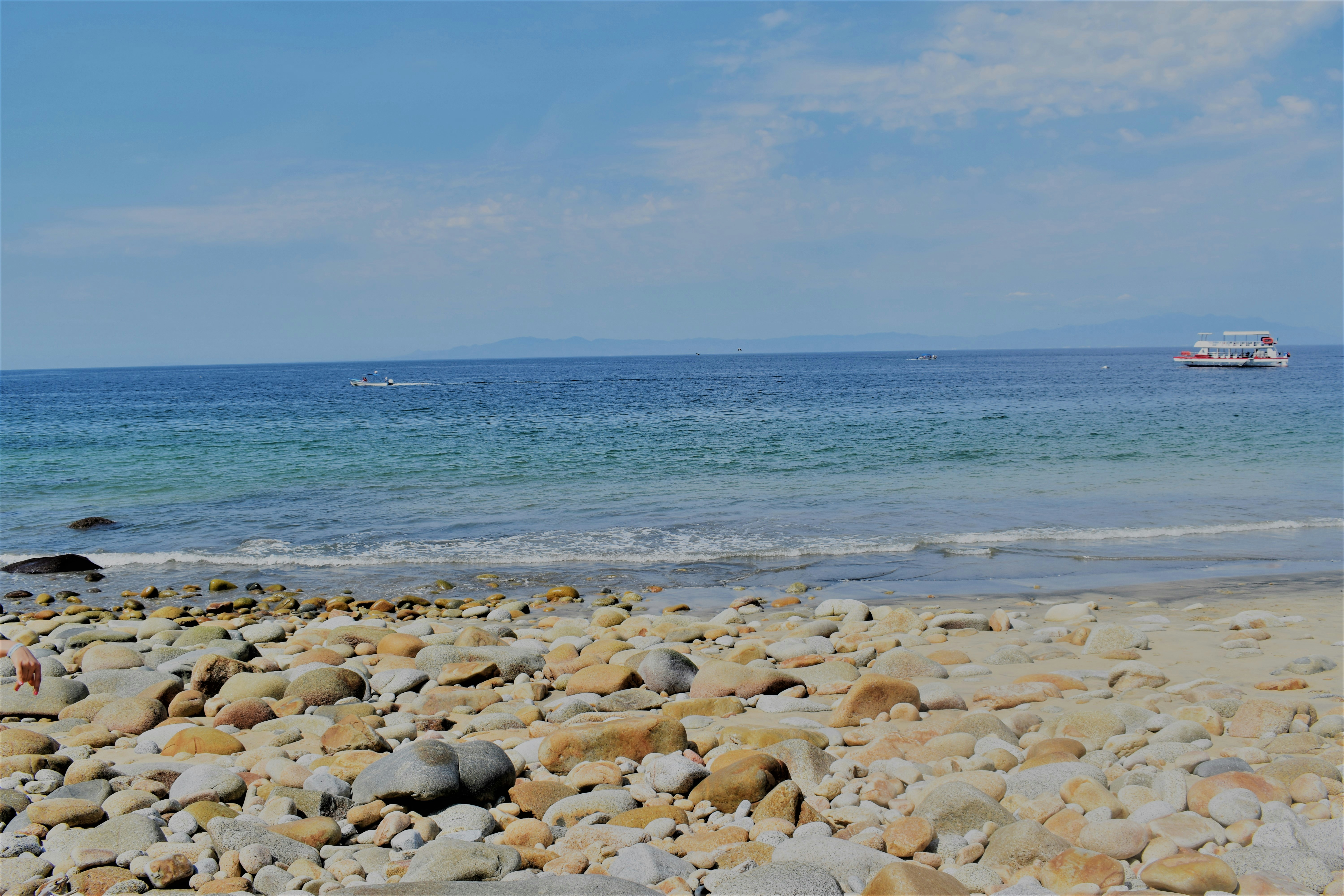 a beach with rocks and a boat in the water