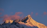 Golden sunrise casting warm light over a rugged mountain peak.