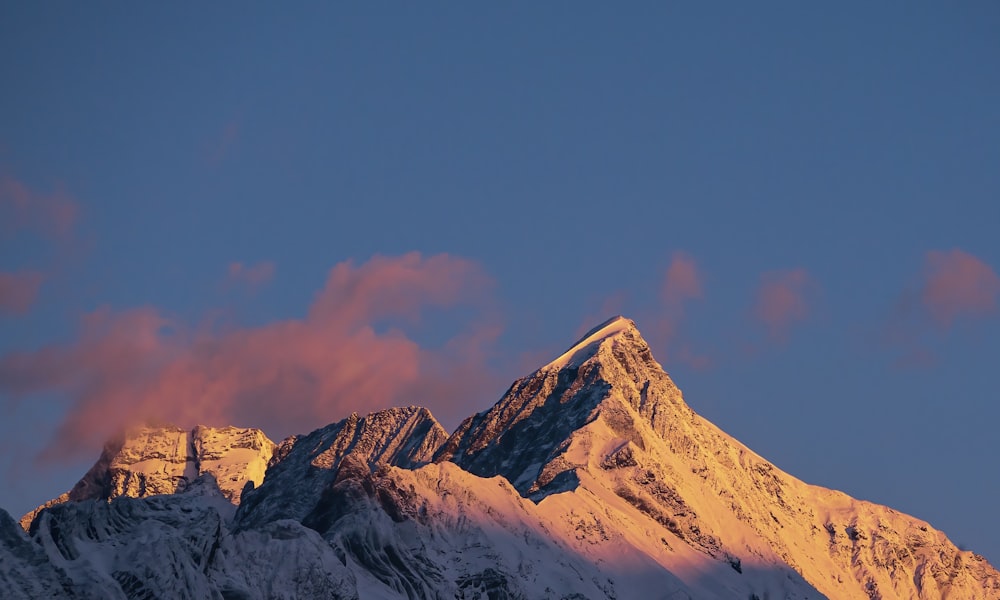 a snow covered mountain with clouds in the sky