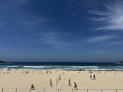 A cheerful scene of people enjoying interactive tech games on a beach with palm trees and ocean waves under a sunny sky.