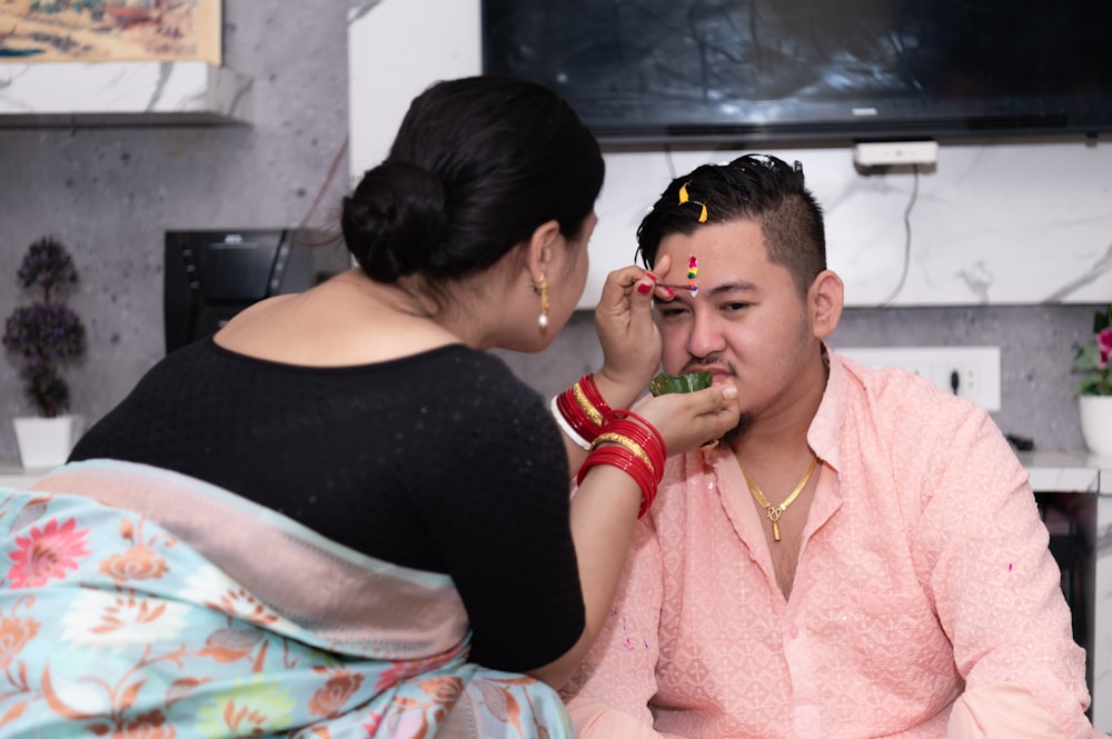 a woman putting makeup on a man's face